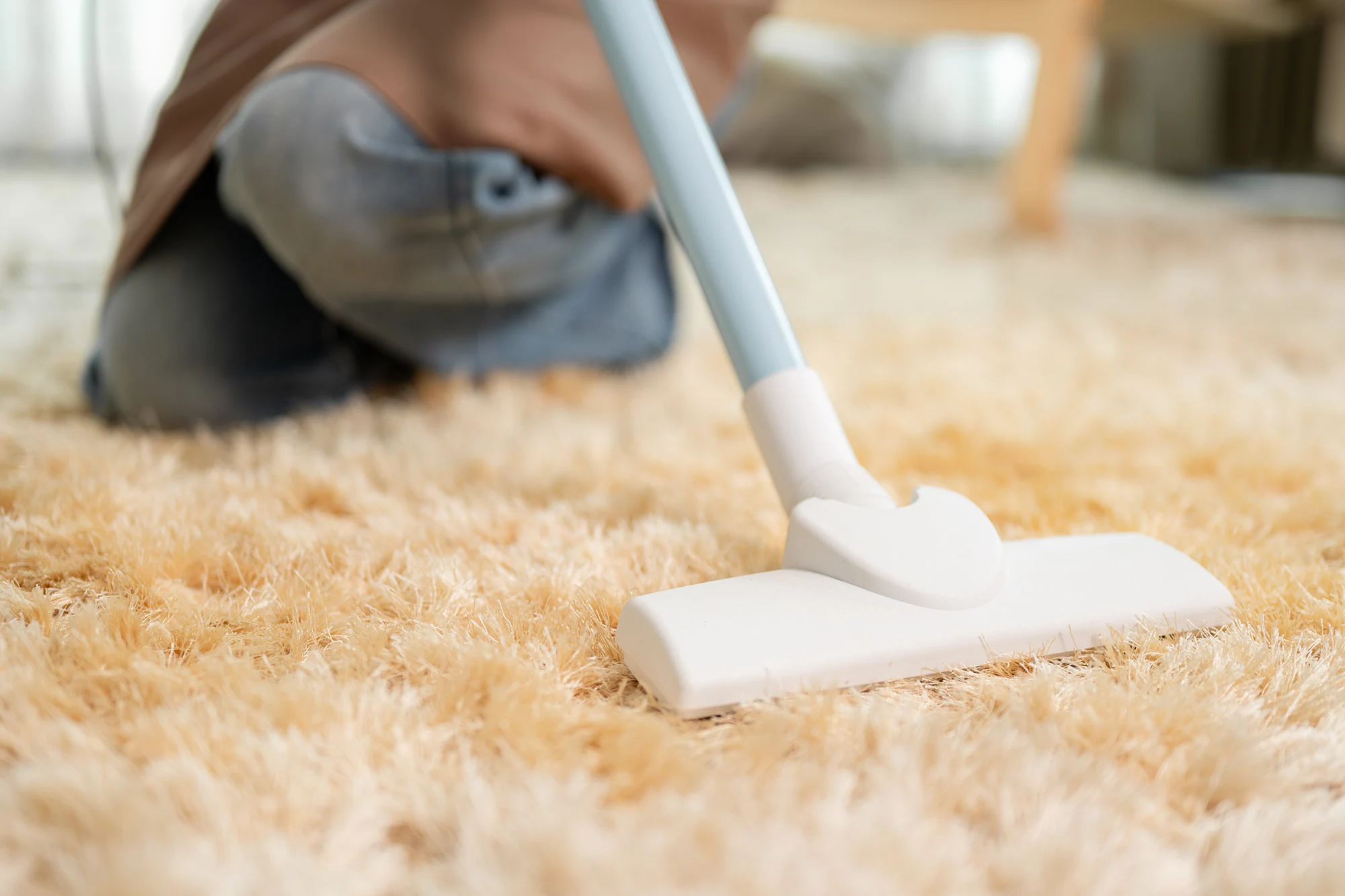 Vacuuming a beige carpet close-up.